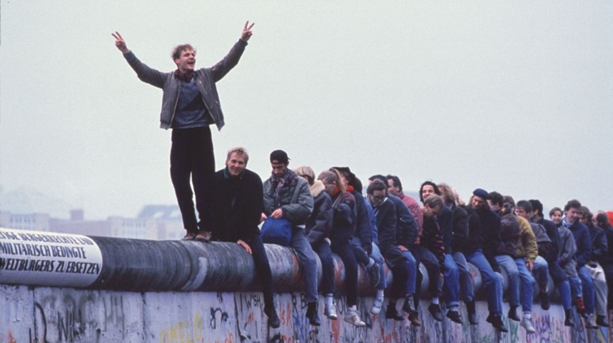 German people standing atop the Berlin Wall