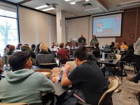 two people presenting to a room full of teenagers