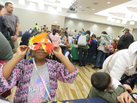 a child holding up a handmade paper mask 